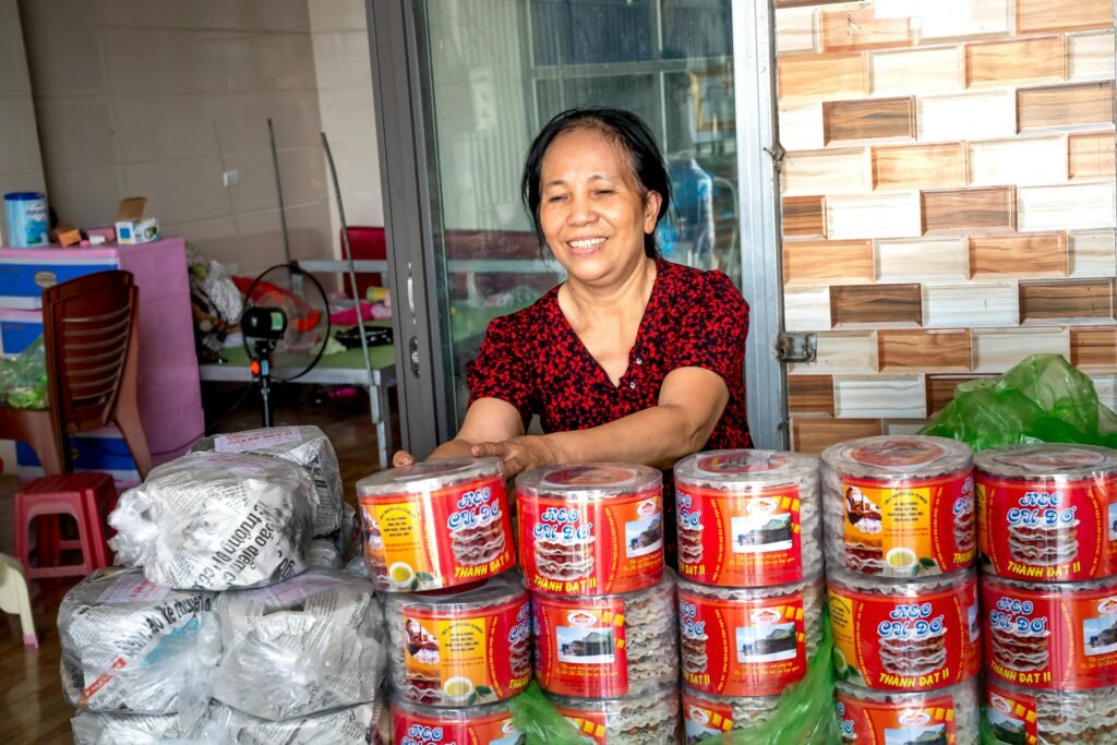 Smiling ethnic vendor against containers with rice cakes
